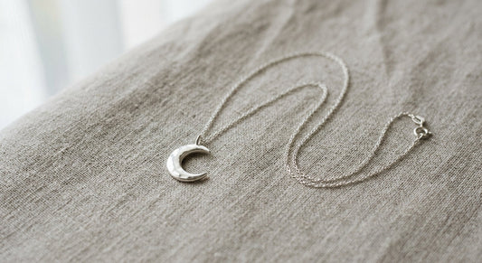 Elegant sterling silver crescent moon necklace on a neutral background