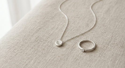 Elegant sterling silver ring and necklace on a neutral background