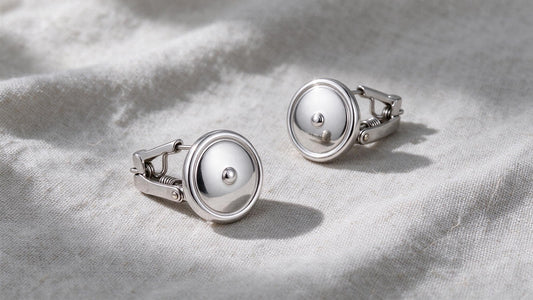 Elegant silver clip-on earrings displayed on a neutral linen surface