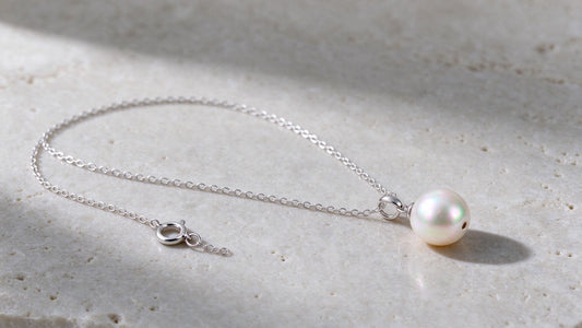 Elegant pearl necklace resting on a neutral surface with soft natural lighting