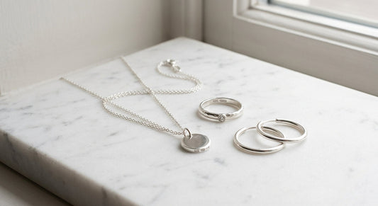 Elegant sterling silver jewelry resting on a clean neutral surface with soft natural lighting