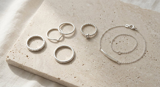 Elegant polished sterling silver jewelry on a neutral surface with soft natural lighting
