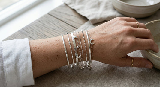A stylish wrist stack of sterling silver bangles and delicate chain bracelets