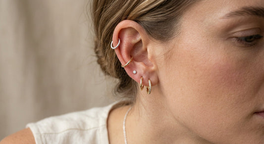 A curated ear stack with elegant sterling silver and gold earrings against a neutral background.