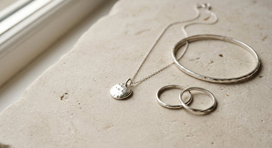 Elegant sterling silver jewelry displayed on a clean neutral surface.
