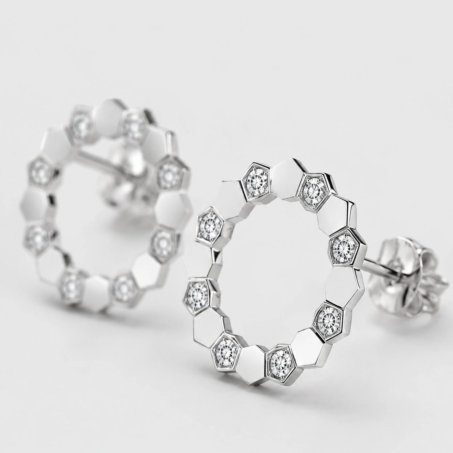 Macro close-up of clear stone settings and polished facets on open circle stud earrings