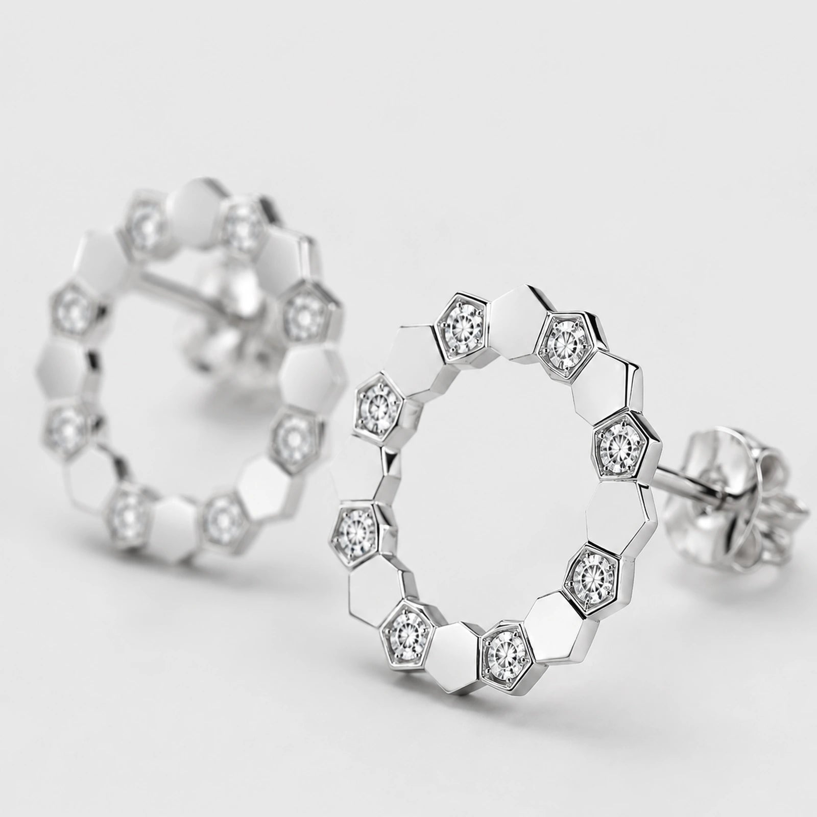 Macro close-up of clear stone settings and polished facets on open circle stud earrings