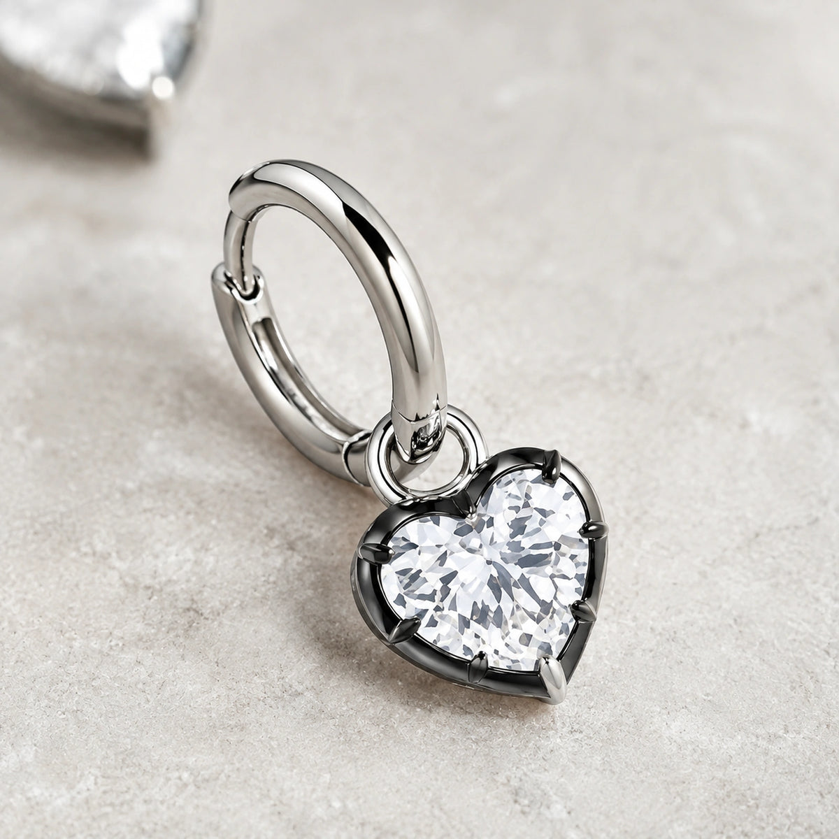 Close-up of a clear heart crystal and polished silver huggie hoop