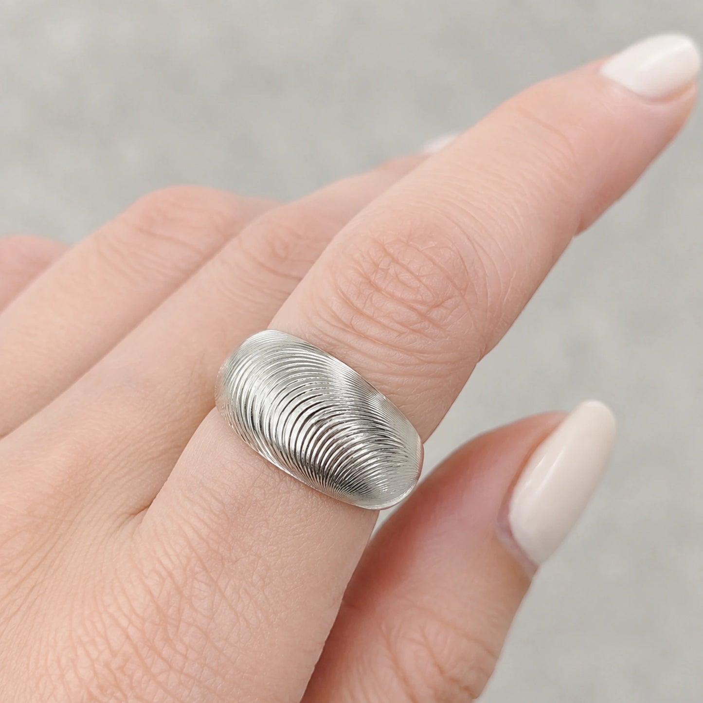 Fingerprint texture silver band ring worn on a woman's finger