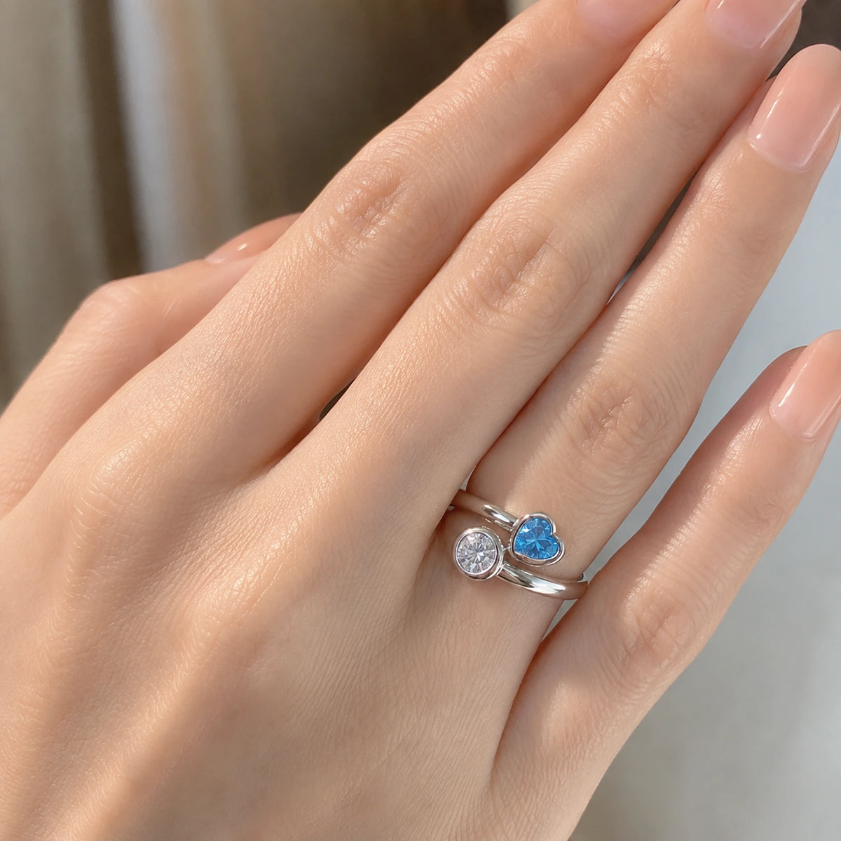 Close wearing view of blue heart sterling silver bypass ring on a woman's hand