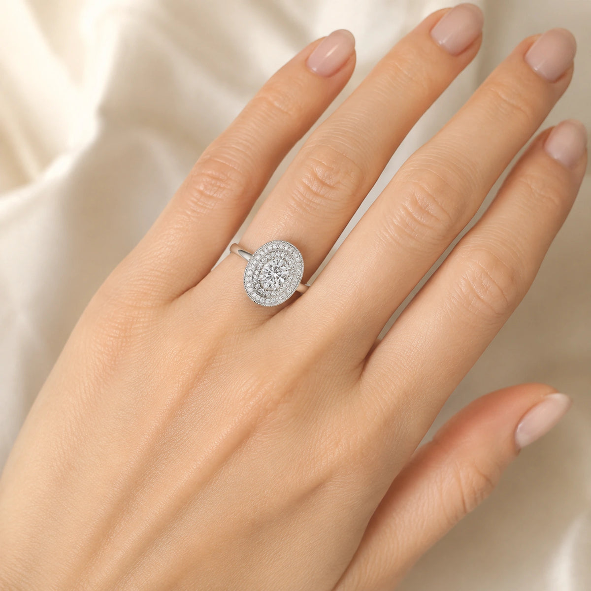 Close view of an oval halo adjustable silver ring worn on a hand