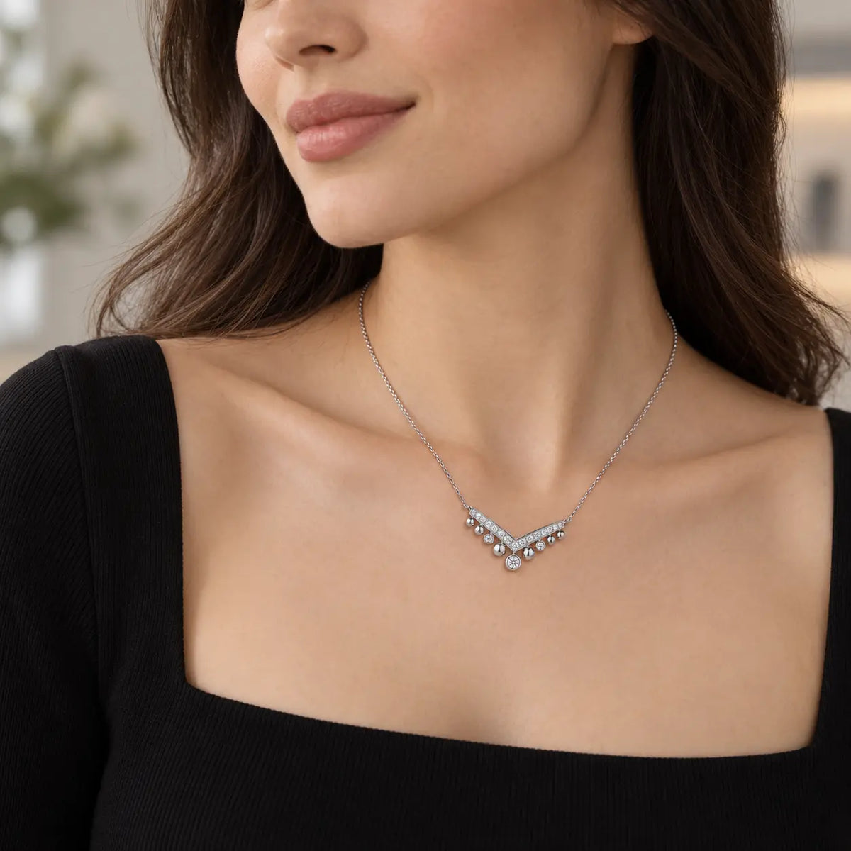 Lifestyle view of a silver crystal chevron necklace worn with a black top.