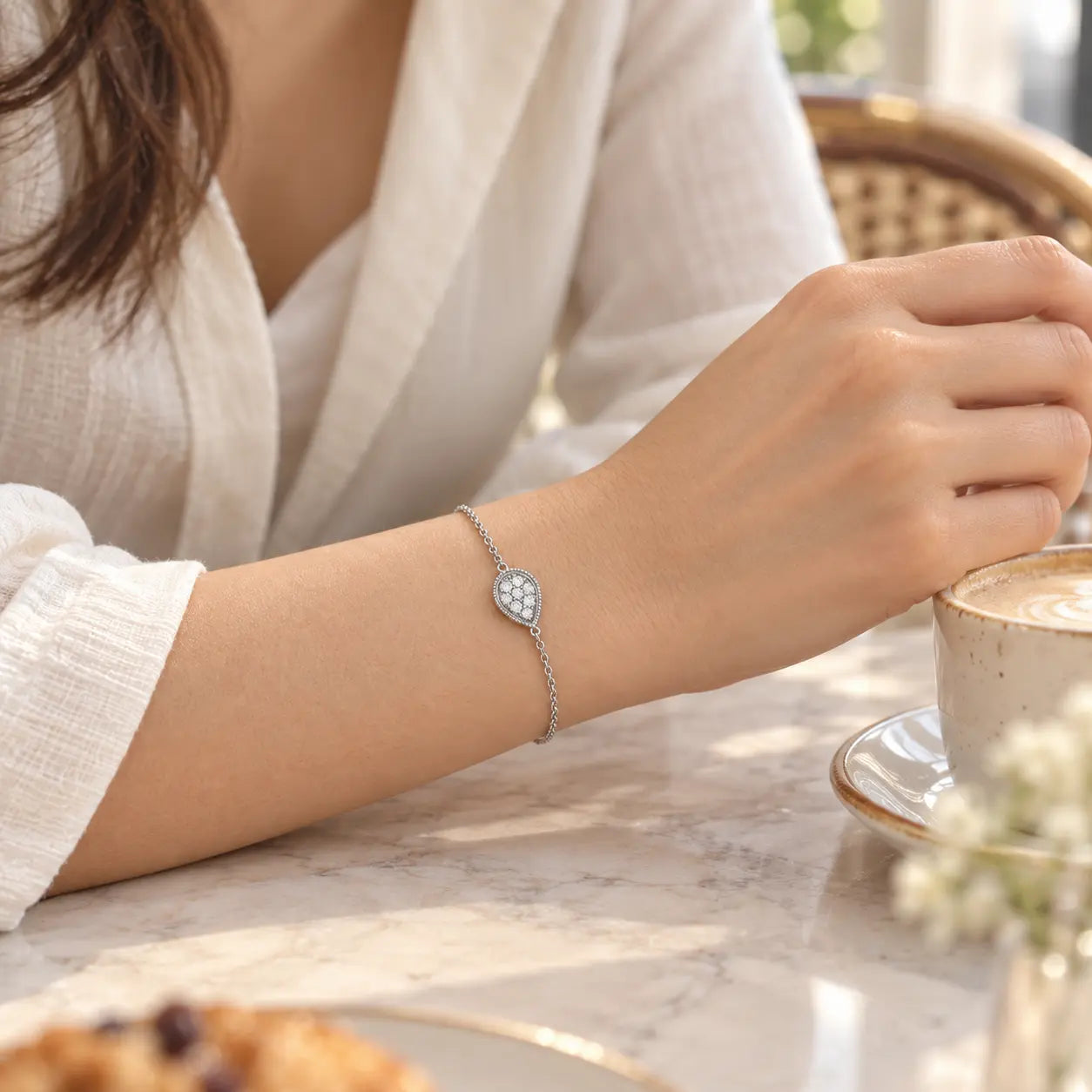 Crystal teardrop bracelet worn in a softly lit everyday cafe setting.
