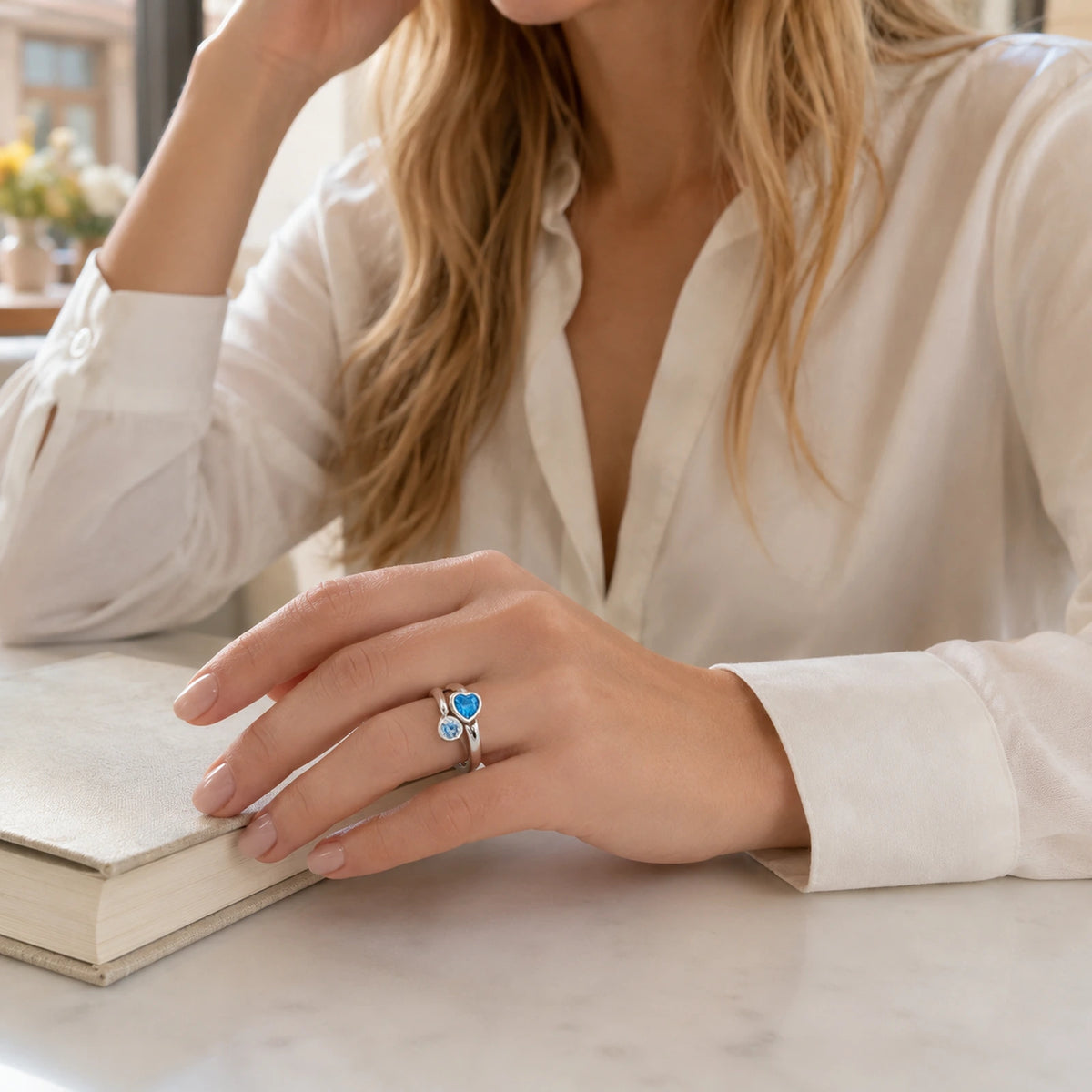 Woman wearing blue heart sterling silver bypass ring in a bright lifestyle setting