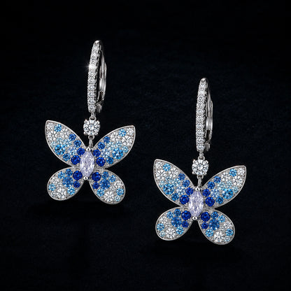 Blue butterfly drop earrings photographed on a premium dark background