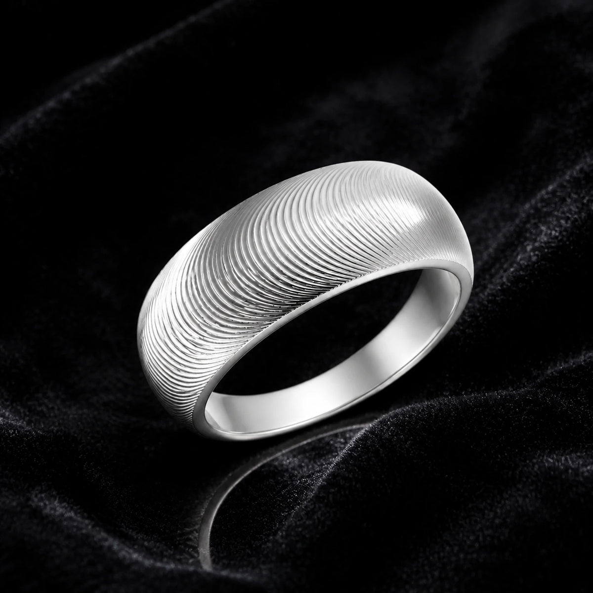 Silver fingerprint texture band ring on dark velvet background