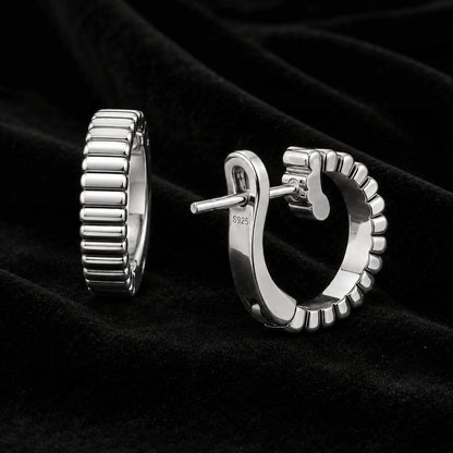 Pair of ribbed silver wide half-hoop earrings on black velvet