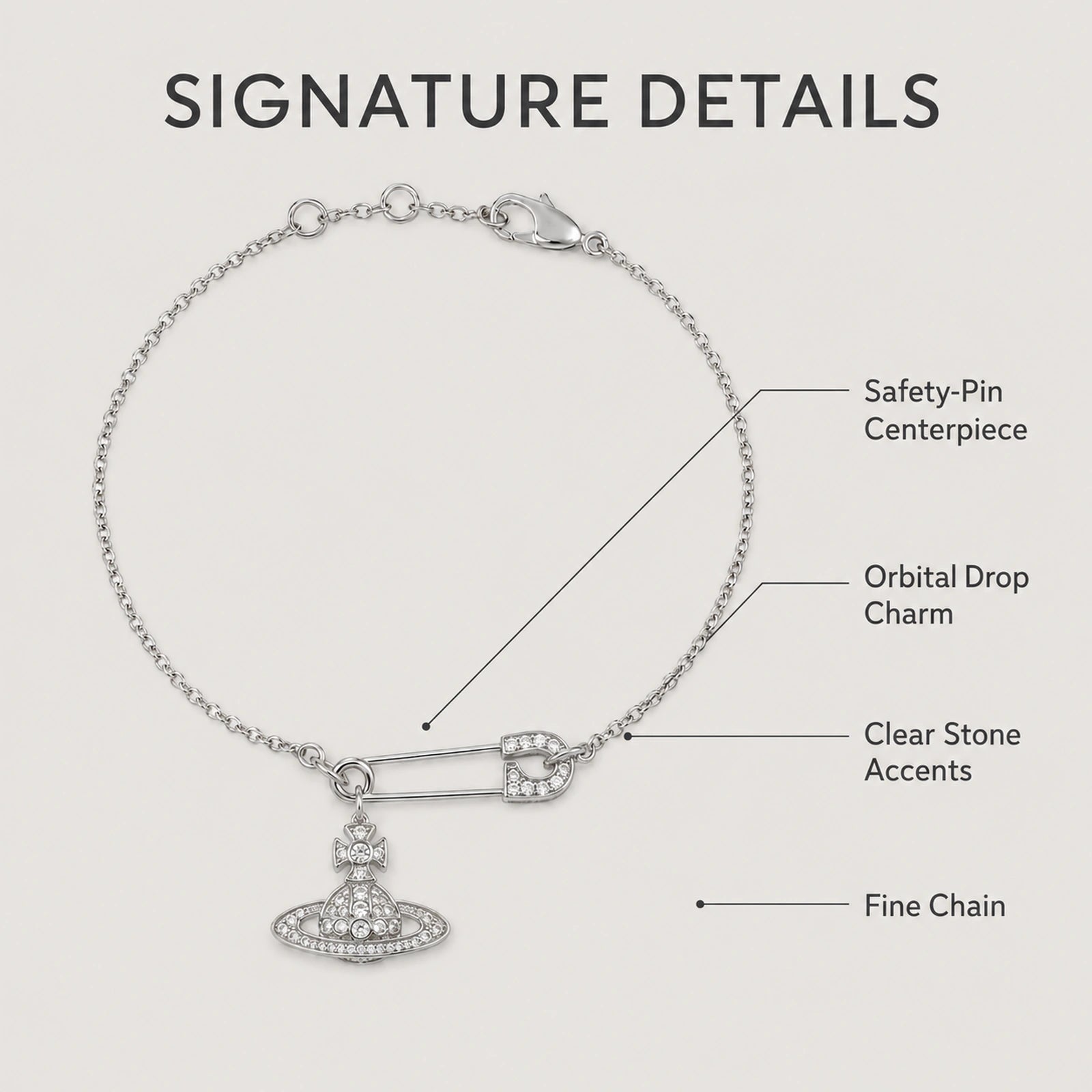 Feature guide highlighting the safety-pin centerpiece, orbital charm, clear stones and fine chain.