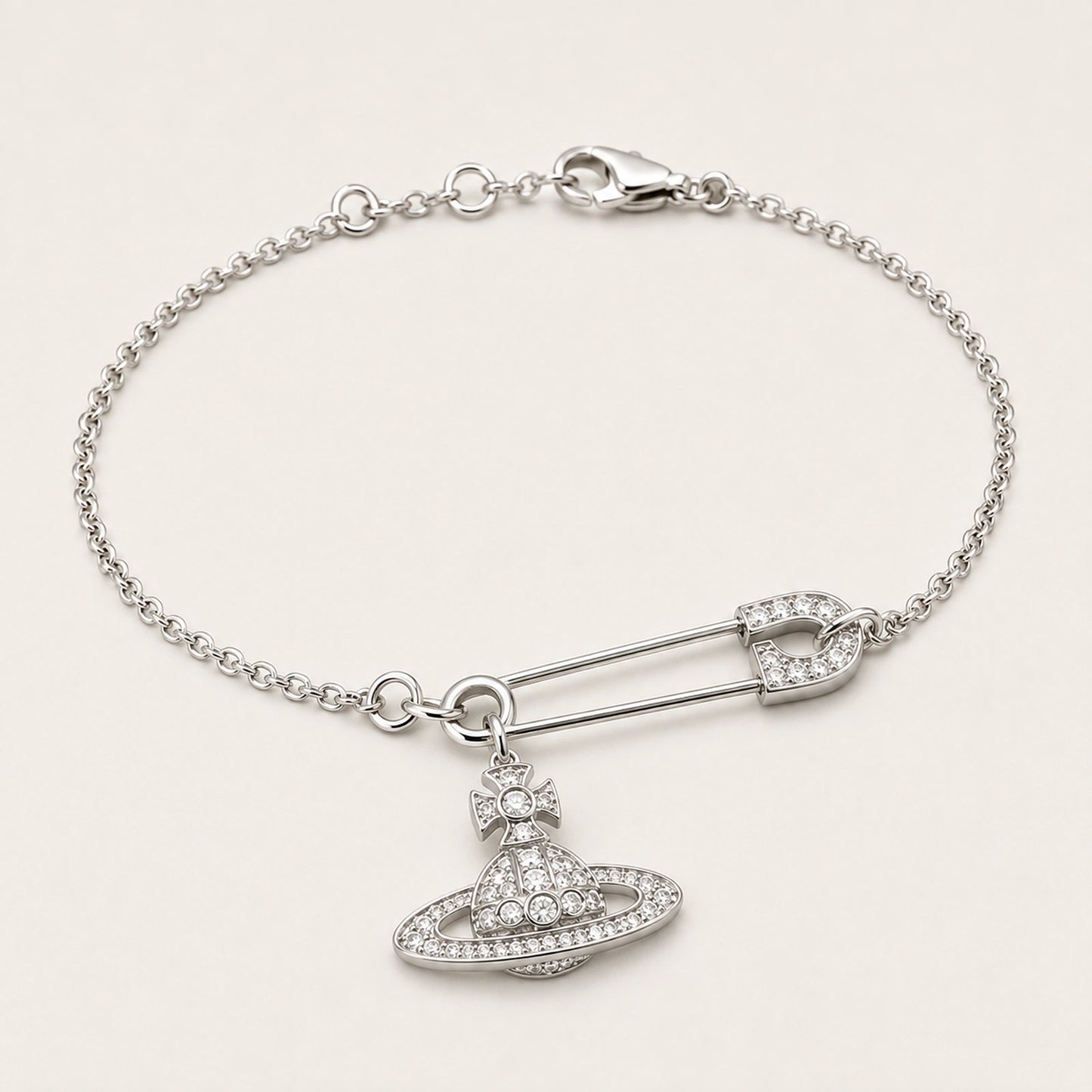 Three-quarter side view of a silver-tone safety pin centerpiece and orbital charm bracelet.