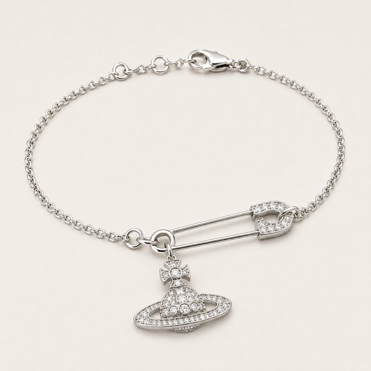 Three-quarter side view of a silver-tone safety pin centerpiece and orbital charm bracelet.