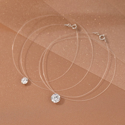 Delicate cross chain and round pendant detail on a silver necklace