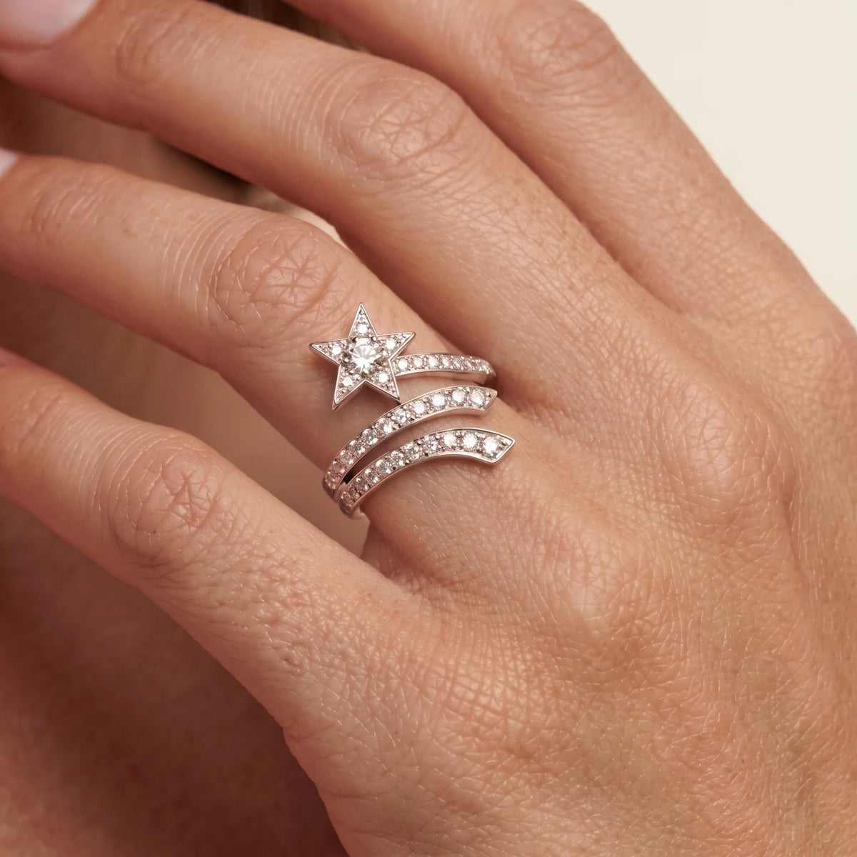 Close-up of a shooting star wrap ring with stone-set curved bands worn on a finger